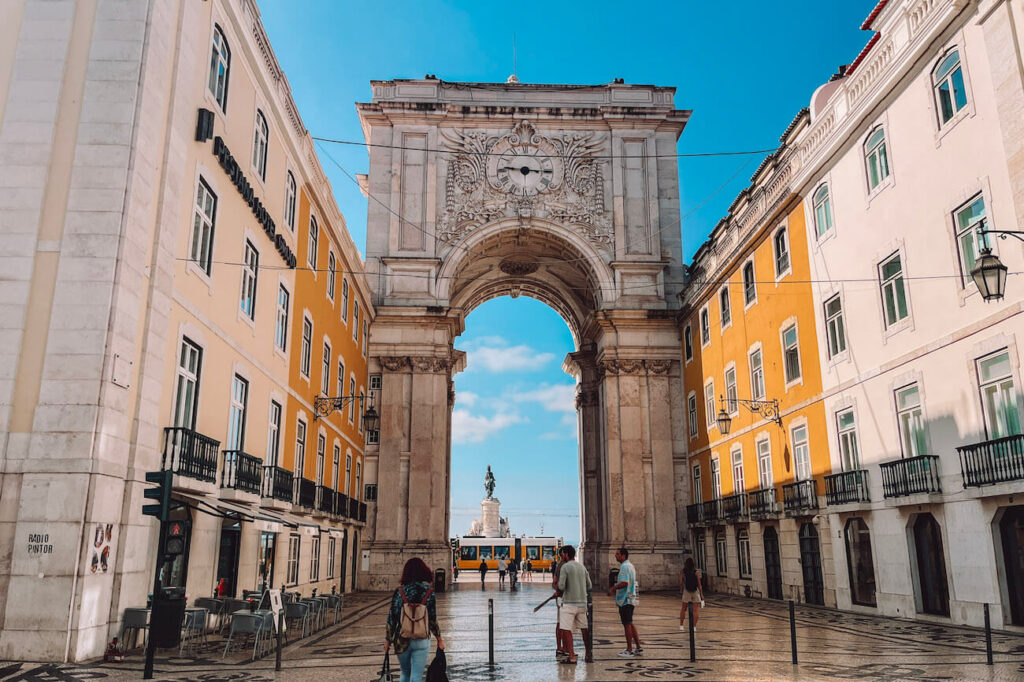View through the Arco da Rua Augusta leading to Praça do Comércio, with a yellow tram and statue visible in the background – an essential stop on a 2-day Lisbon itinerary.