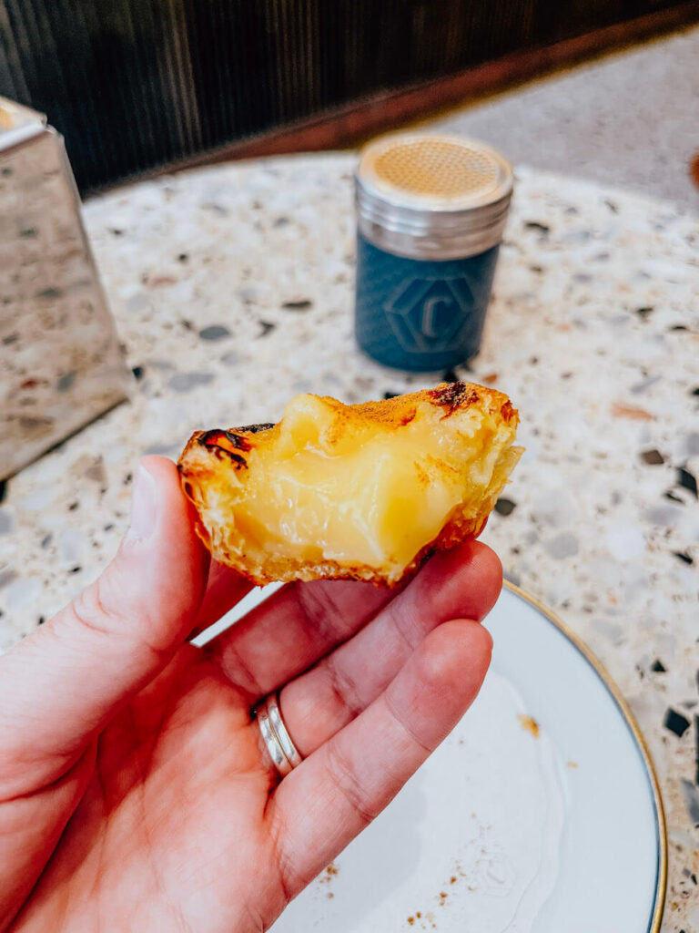 Hand holding a half-eaten pastel de nata, showing the creamy custard filling – how many pasteis de nata can you eat in 2 days in Lisbon?