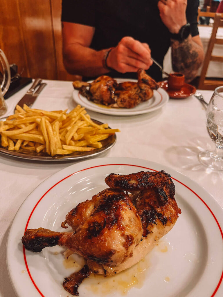 Grilled piri piri chicken served with fries on a white plate in a traditional Portuguese restaurant – a popular dinner option during a weekend in Lisbon.