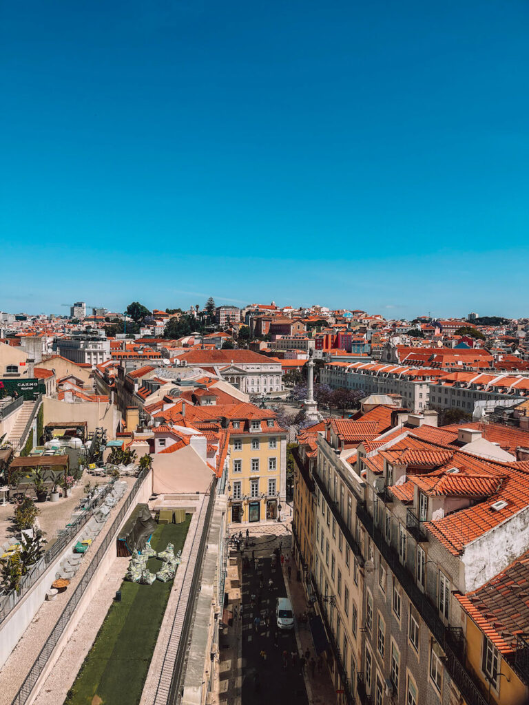 View over Lisbon's red rooftops and winding streets, with Rossio Square visible in the distance – a beautiful cityscape to admire during 2 days in Lisbon. This is the view from the Elevador de Santa Justa.