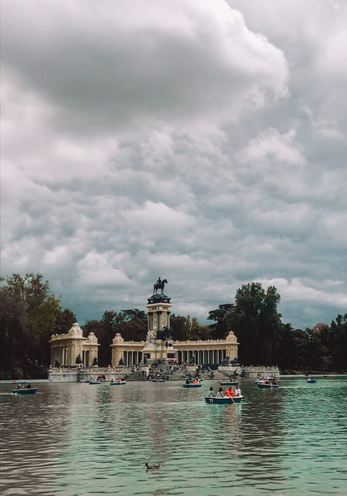 Monument to Alfonso XII overlooking the boating lake in Retiro Park, with people rowing – a relaxing highlight for those spending 2 days in Madrid.
