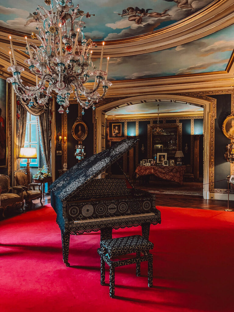 Ornate salon in Madrid with a grand chandelier and a patterned piano under a painted ceiling – part of a cultural visit worth including when exploring Madrid in 2 days. This is the interior of Palacio Liria.