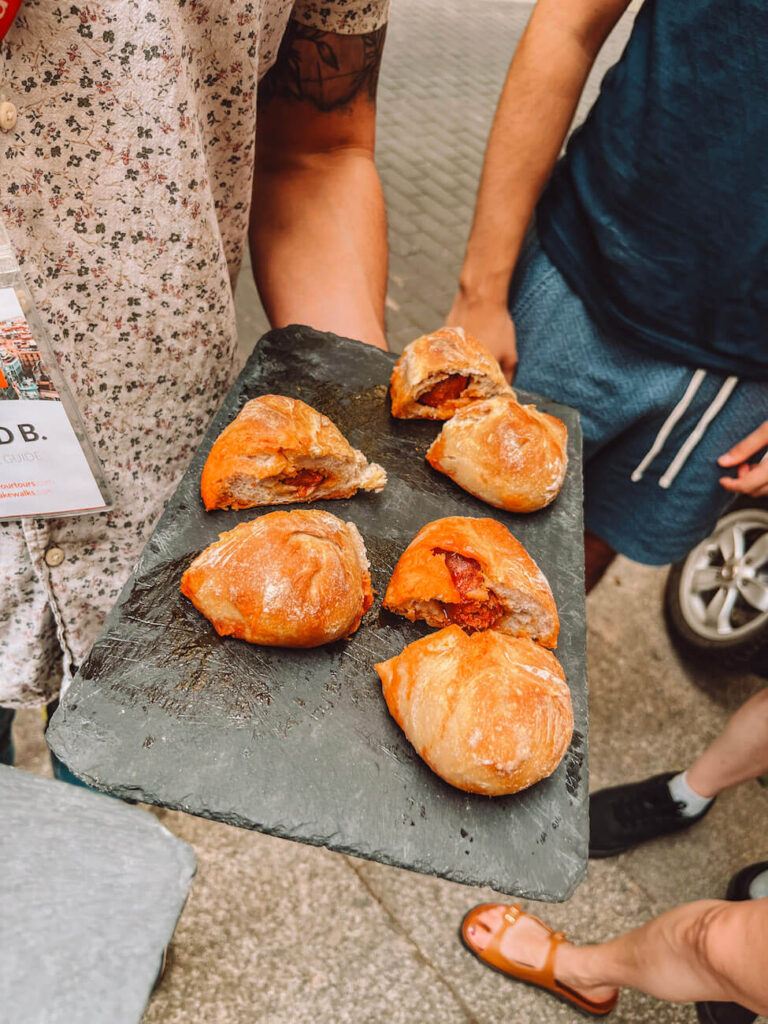Freshly baked rolls stuffed with chorizo served on a tray during a Madrid food tour – a tasty highlight to include in your 2-day Madrid itinerary. A Madrid food tour with Devour Tours is a must!