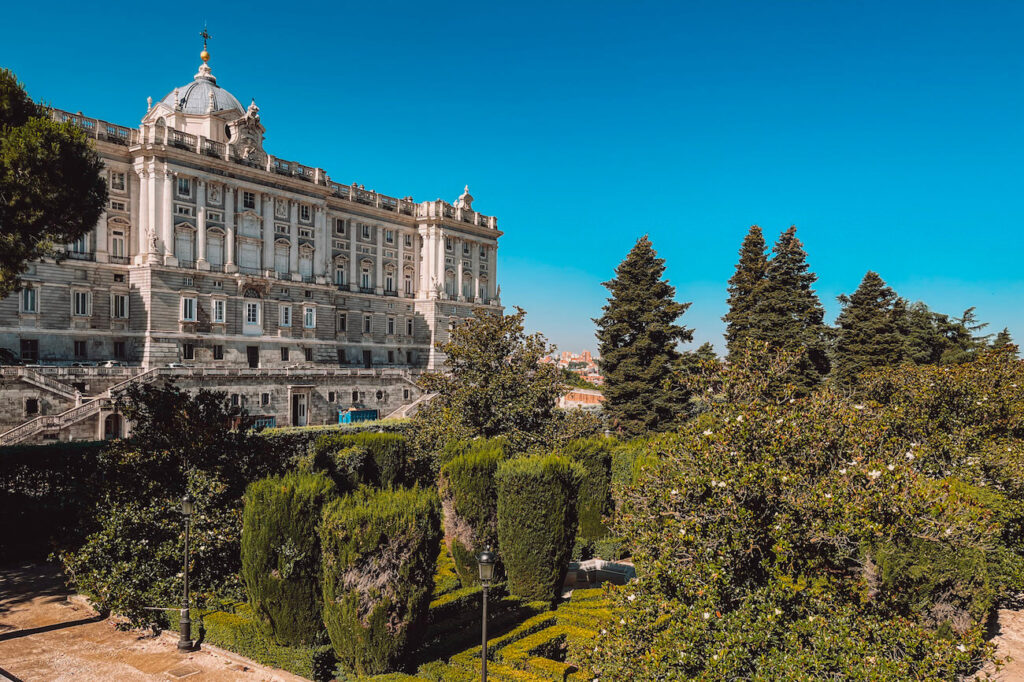 Side view of the Royal Palace of Madrid with neatly kept palace gardens in the foreground – the Sabatini Gardens are a beautiful spot to see when spending 2 days in Madrid.