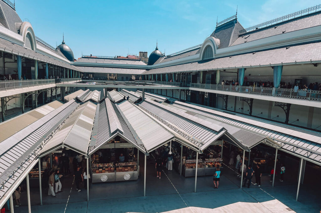 Aerial view of the renovated Mercado do Bolhão in Porto, with market stalls under a metal roof surrounded by elegant upper-floor balconies – a traditional market to visit in Porto.