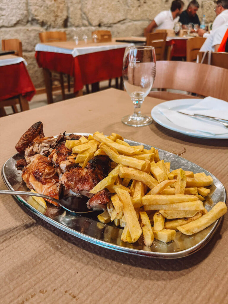 Traditional Portuguese grilled chicken with fries served on a metal tray in a rustic Porto restaurant called Pedro dos Frangos – a hearty meal to enjoy during a weekend in Porto.