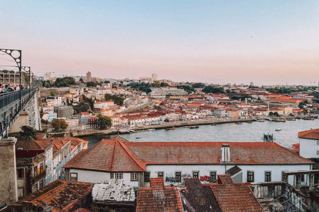 Panoramic sunset view from the Dom Luís I Bridge overlooking the Douro River and red-roofed houses in Vila Nova de Gaia – a stunning photo spot during your 2 days in Porto.