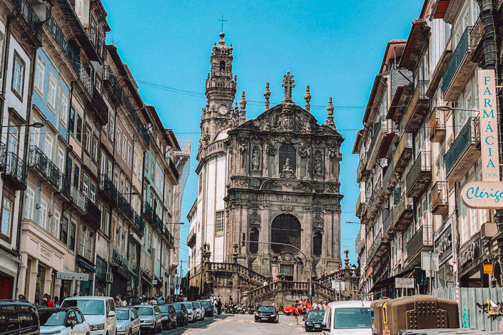 Ornate façade of Igreja dos Clérigos with the iconic Clérigos Tower rising behind it, viewed from a busy city street – a must-visit landmark on your Porto itinerary.