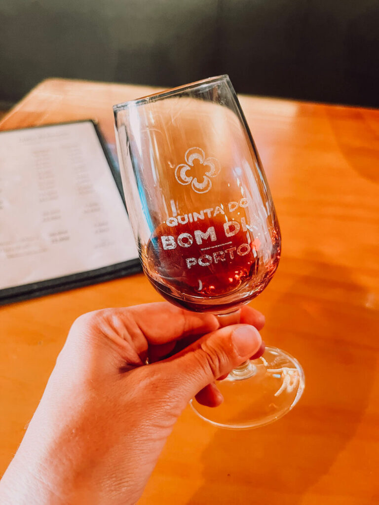 Hand holding a glass of port wine from Quinta do Bom Dia during a tasting session – sampling port is a key activity on a 2-day Porto itinerary.