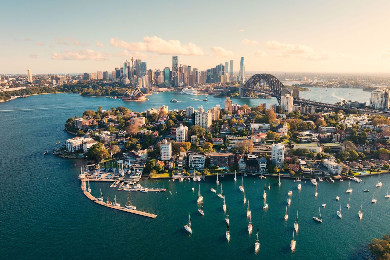 Aerial view of Sydney Harbour with the Opera House, Harbour Bridge, and sailing boats at sunset – an iconic starting point for a 2-week Australia itinerary.