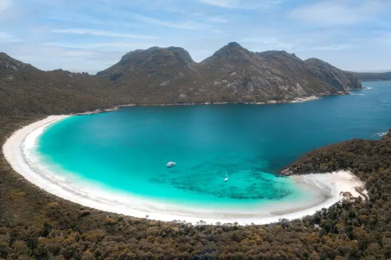 A stunning view of Wineglass Bay in Freycinet National Park, Tasmania — a must-see stop on any 4 weeks in Australia trip. This Australia itinerary highlight features a perfect crescent of white sand, turquoise water, and rugged granite mountains, with boats anchored in the bay.