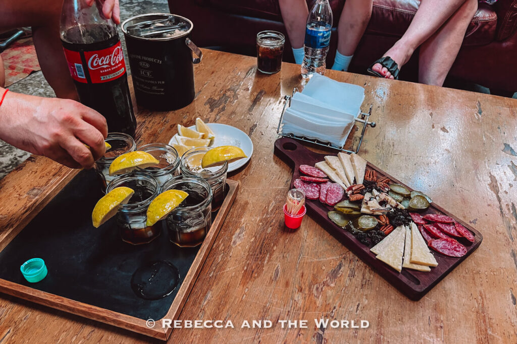 Shared drinks (Fernet and Coke) and a charcuterie board with cheeses and cured meats during Asado Adventure, complementing the Argentine barbecue experience.