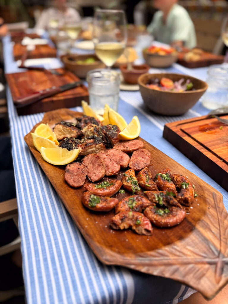 Platter of grilled chorizo and chinchulines, sweetbreads with lemon wedges and chimichurri at Asado Adventure, part of a classic Argentine asado experience in Buenos Aires.