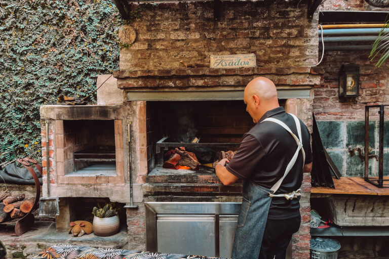 Frank, the host of Asado Adventure in Buenos Aires, managing the grill and firewood, highlighting the hands-on nature of an Argentine barbecue in Buenos Aires.