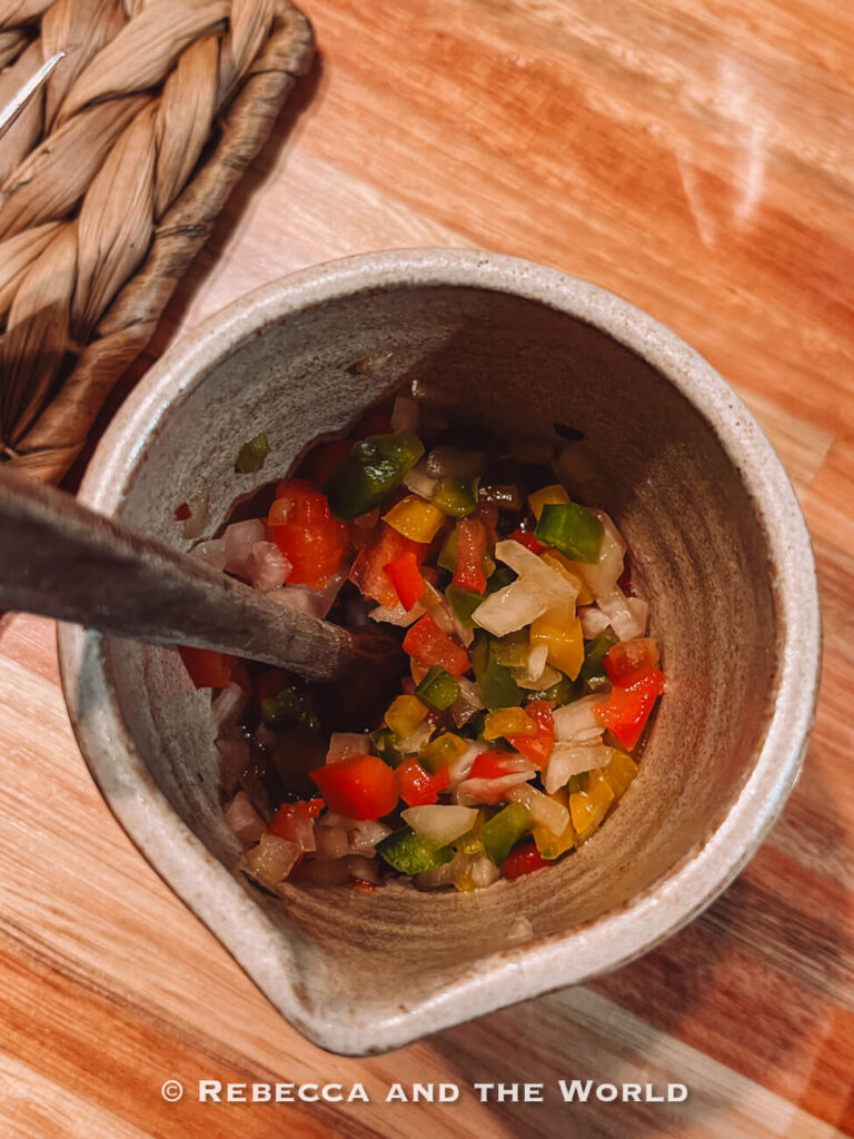 A small ceramic bowl filled with freshly chopped salsa made of tomatoes, onions, and peppers, served as a side during the Buenos Aires asado experience at Betty and Marcelo.
