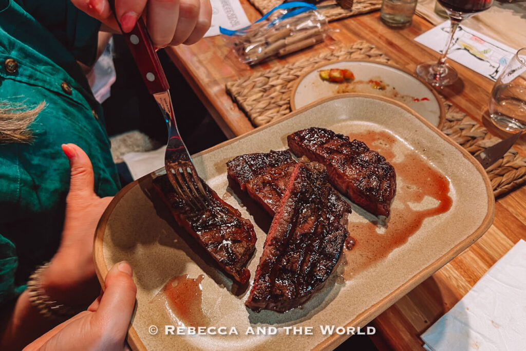 A diner cutting into a juicy grilled steak on a plate, showing the tender interior as part of the meal at Betty and Marcelo Buenos Aires during the Buenos Aires asado experience.