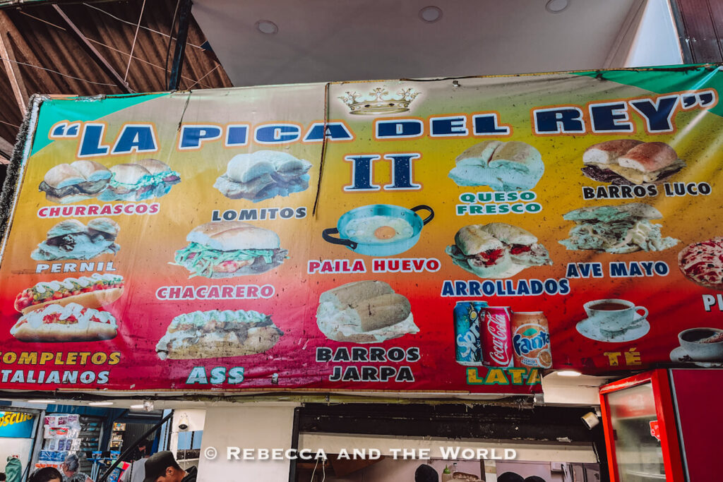 Colorful menu board listing Chilean sandwiches like chacarero and lomito inside a local eatery, offering insight into what to eat in Chile during a Santiago food tour.