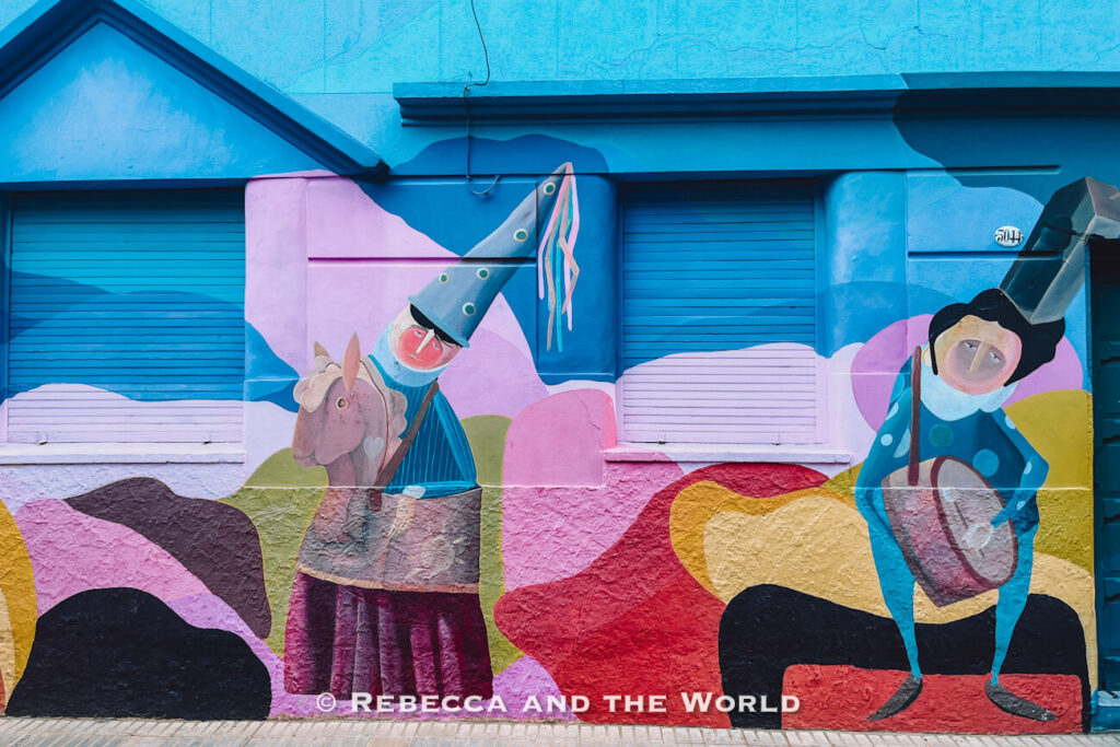 A colorful mural on a building wall depicting stylized figures and abstract shapes, seen while walking between stops on a Sherpa food tour Buenos Aires.