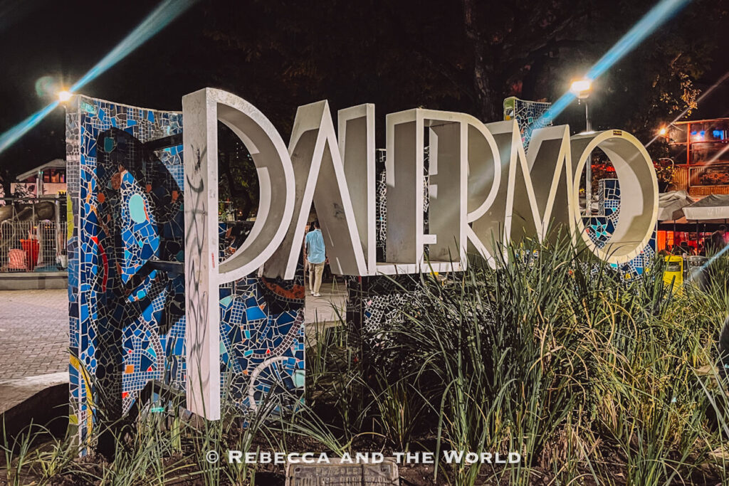 Nighttime street scene with a large “Palermo” sign decorated with colorful mosaic tiles, photographed during a Buenos Aires food tour while exploring the neighborhood.