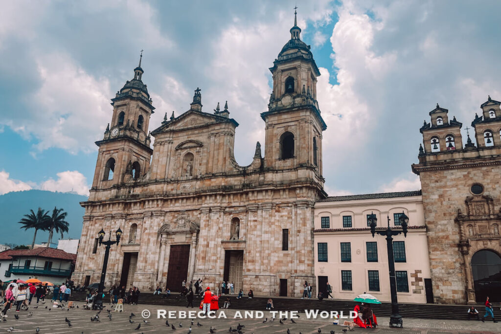 Wide view of Bogotá’s main cathedral façade with twin bell towers overlooking a plaza filled with pedestrians and pigeons, a highlight of a Bogotá itinerary.