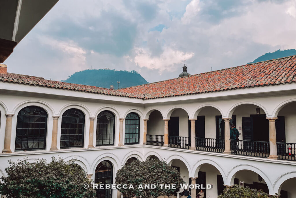 White colonial courtyard with arched walkways, tiled roofs, and mountain views beyond the building, featured in a 2-day Bogotá itinerary.
