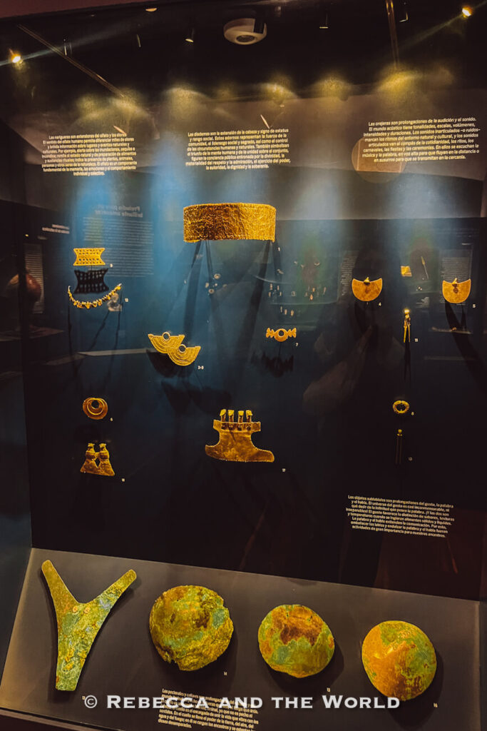 Museum display case featuring pre-Columbian gold jewelry and ceremonial objects illuminated against a dark background, one of the top things to do in Bogotá.