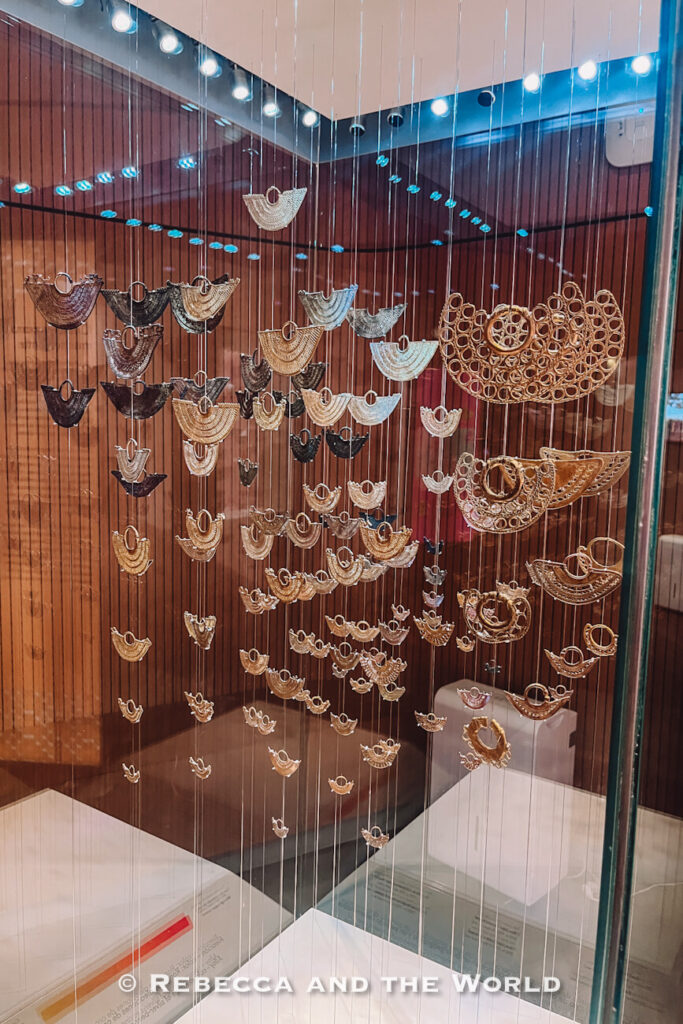 Gold-coloured ornaments hang on fine wires inside a glass museum display case. Visiting the Museo del Oro (gold museum) is something to include in 3 days in Cartagena.