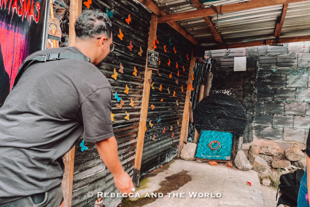 Person throwing a metal disk toward a target in a rustic game area with butterfly decorations during a Bogot&aacute; food tour. This is tejo, a fun explosive game!