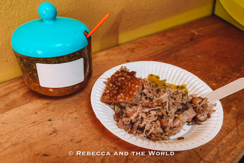 Paper plate of shredded roasted pork with crispy skin, beans, and green sauce, showing some of the best food in Bogot&aacute;.