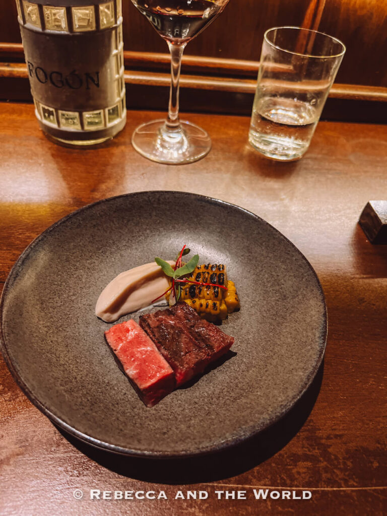 Grilled steak plated with charred corn, creamy sauce, and microgreens at Fogon Asado, a popular fine dining experience and one of the top things to do in Buenos Aires.