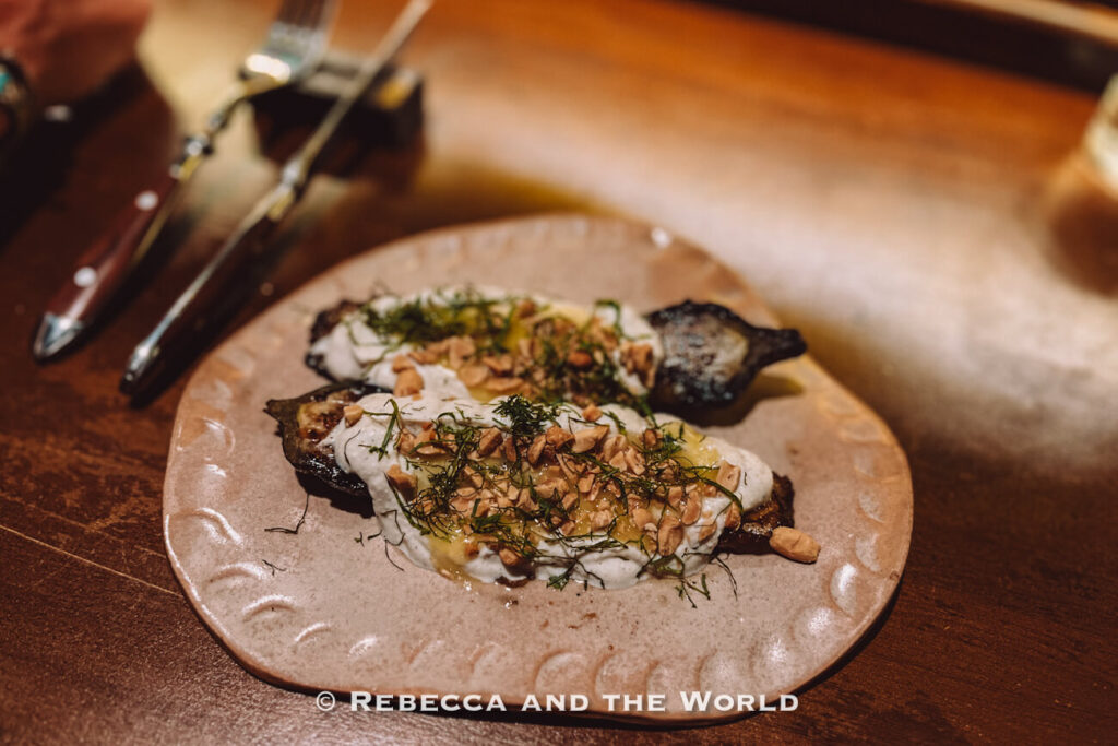 Roasted eggplant topped with creamy sauce, herbs, and chopped nuts served at Fogon Asado restaurant.