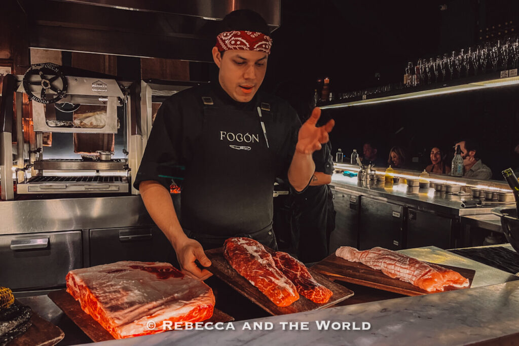 Chef presenting large cuts of raw beef and fish at the counter of Fogon Asado, a popular answer to what to do in Buenos Aires for food enthusiasts.