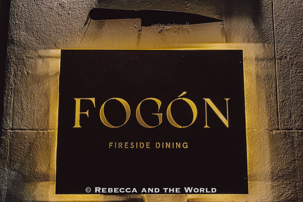 Illuminated Fogon Fireside Dining sign mounted on a stone wall outside the restaurant in Buenos Aires.