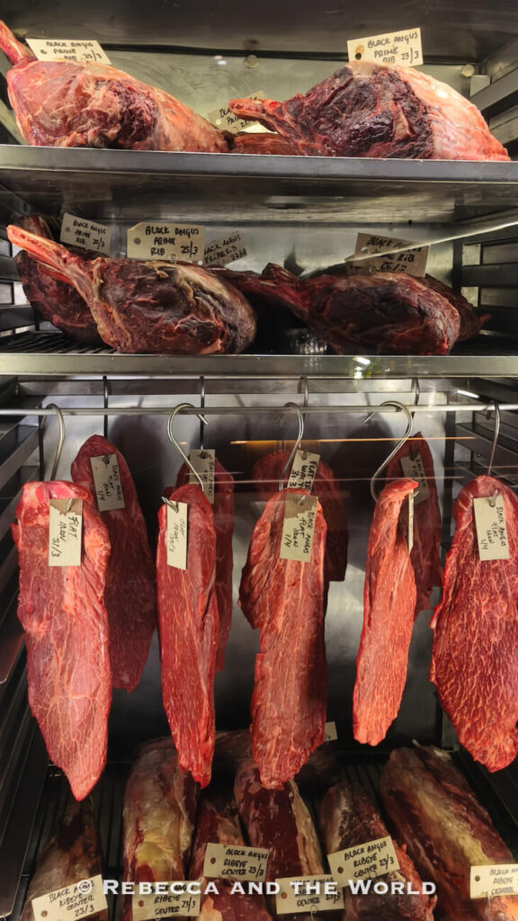 Large cuts of dry-aged beef stored on metal racks inside the Fogon Asado meat aging room in Buenos Aires.