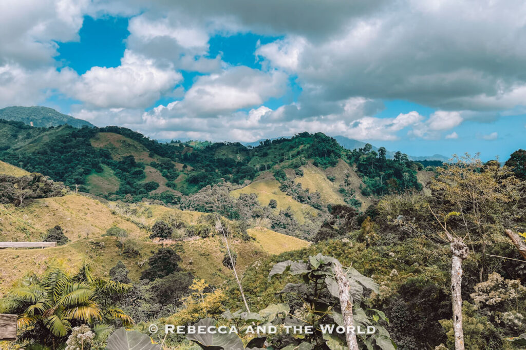 Rolling green mountains and forested hills under dramatic clouds along the Lost City hike route in the Sierra Nevada during the Ciudad Perdida trek.