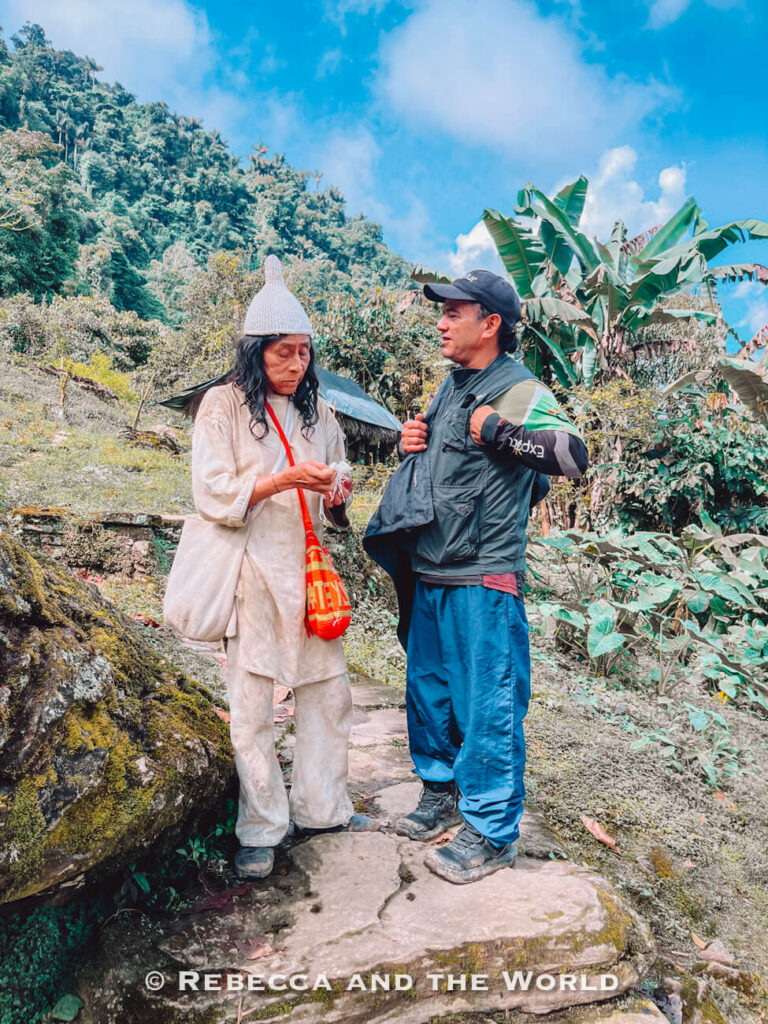 Indigenous Kogi person standing beside a local guide during the Lost City trek through Ciudad Perdida, surrounded by lush greenery and jungle vegetation.