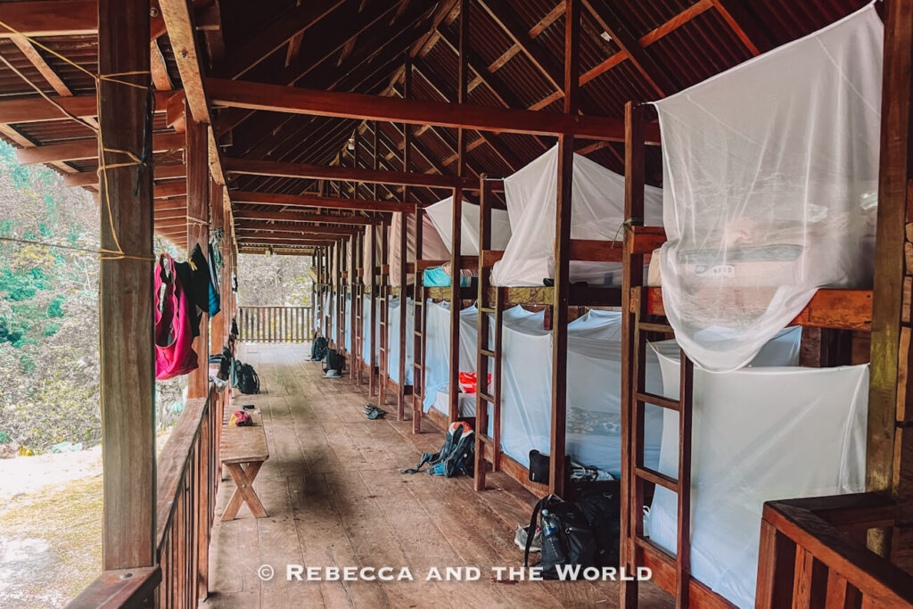 Wooden bunk beds with mosquito nets inside a rustic trekking camp accommodation on the Ciudad Perdida hike.