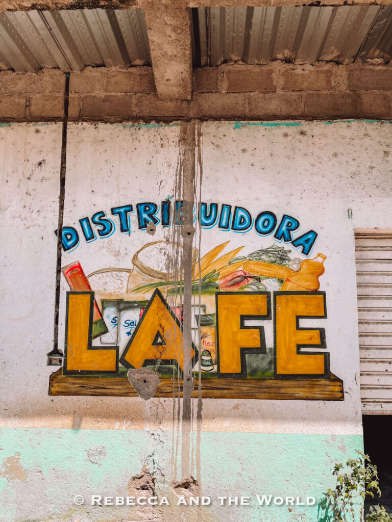 Painted wall sign reading “Distribuidora La Fe” on a rustic building in a rural Colombian village along the trek route.