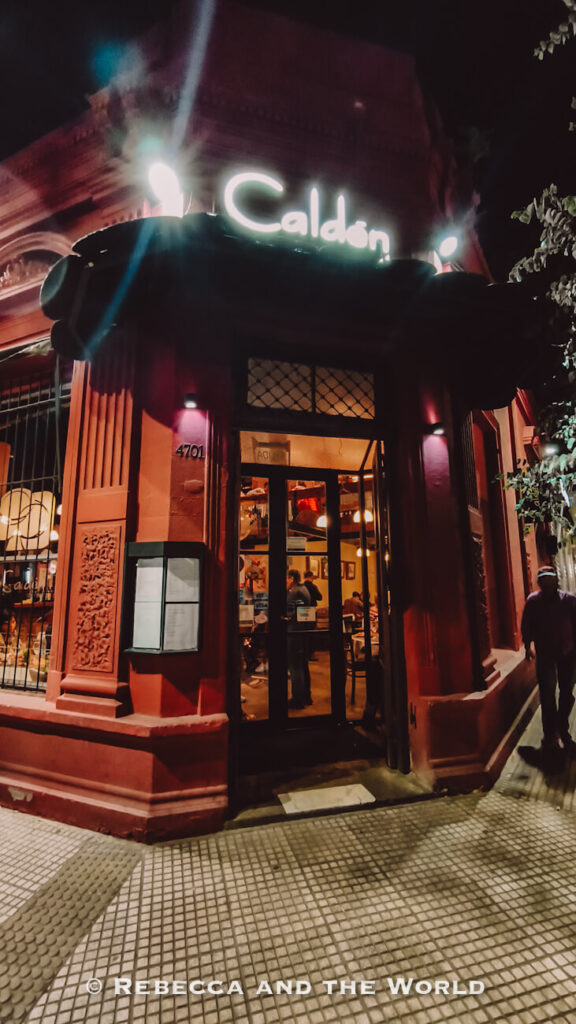 Nighttime entrance to El Caldén del Soho, a classic steak restaurant in Buenos Aires, with glowing signage and warm lights spilling onto the sidewalk.