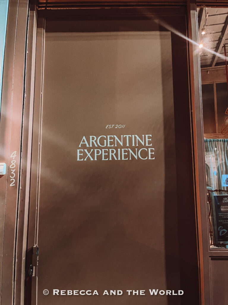 Exterior entrance door with The Argentine Experience logo displayed in white lettering, photographed at night in Buenos Aires as part of a guide to what to do in Buenos Aires.