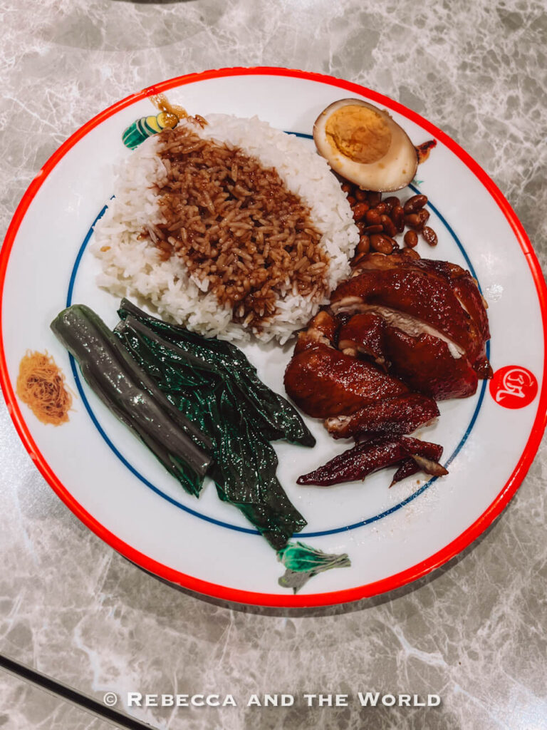 Singapore-style soy sauce chicken served with rice, leafy greens, peanuts and half a braised egg on a patterned plate. Hawker Chan is a must-stop on a Singapore foodie itinerary.