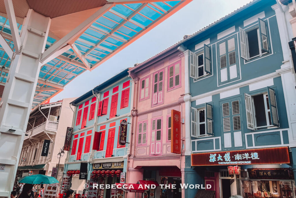 Colourful heritage shophouses with red, pink and grey-green façades and traditional shuttered windows along Smith Street in Singapore’s Chinatown.
