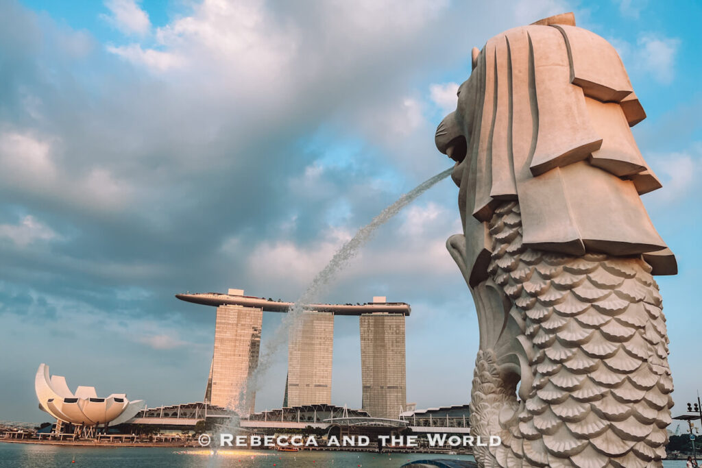 Close view of the Merlion spraying water into Marina Bay, with Marina Bay Sands and the lotus-shaped ArtScience Museum behind it.