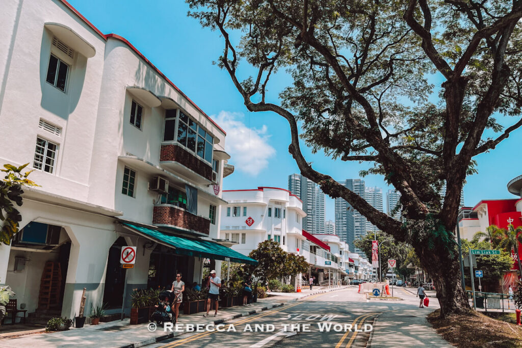 Tree-lined Lim Liak Street in Tiong Bahru, with white Streamline Moderne apartment blocks, curved balconies and modern residential towers in the background.