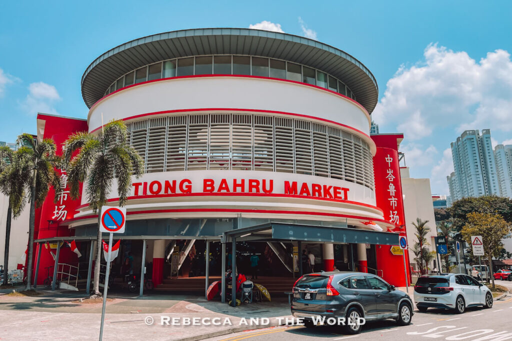 Rounded red-and-white façade of Tiong Bahru Market beneath a bright blue sky, a worthwhile food stop during 2 days in Singapore.