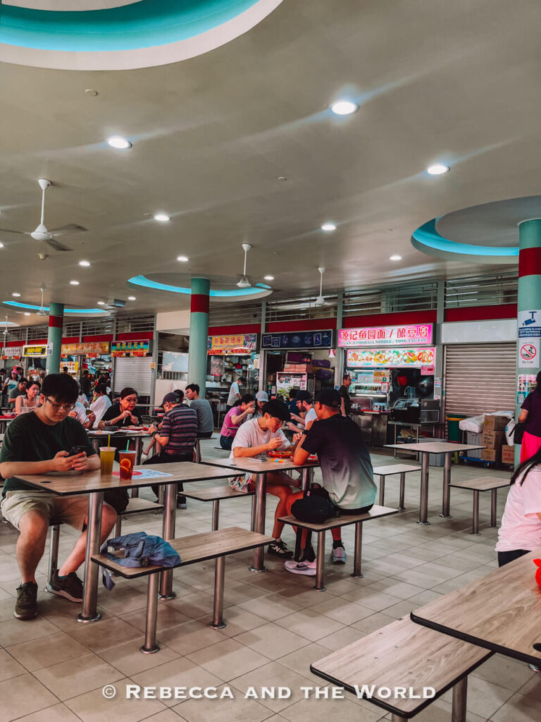 Diners seated at tables among local food stalls inside Tiong Bahru Market and Food Centre, one of the best places to experience Singapore’s hawker culture.