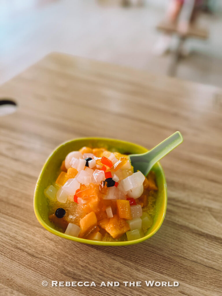 Bowl of colourful ice jelly dessert topped with diced fruit, translucent jelly cubes and small black pearls at Tiong Bahru Food Centre.