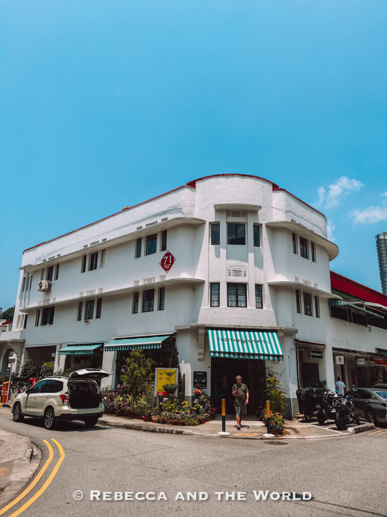 White Streamline Moderne apartment building with rounded corners, green striped awnings and flower-filled storefronts in Tiong Bahru.