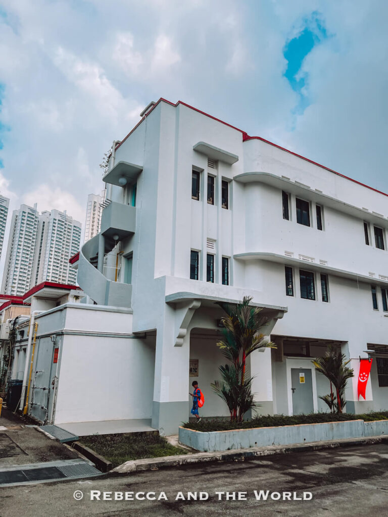 White Art Deco apartment building with curved corners and red roof trim in the Tiong Bahru heritage neighbourhood, a less touristy addition to a Singapore itinerary.