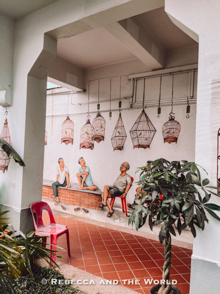 Tiong Bahru mural showing three elderly men chatting beneath hanging birdcages, inspired by the neighbourhood’s former bird-singing corner.